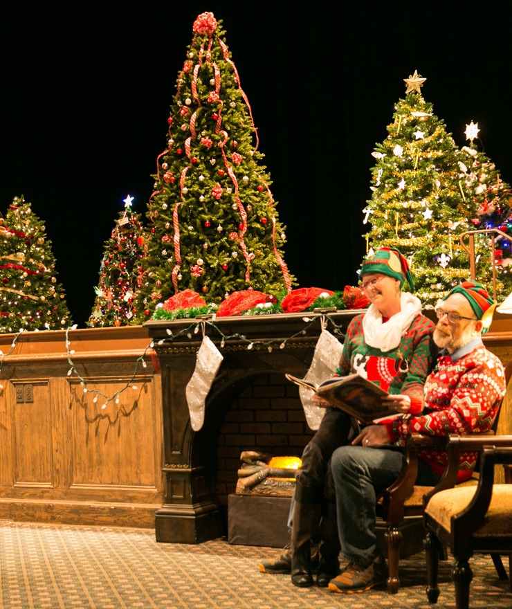 Mercer professors Dr. Carol Bokros and Dr. Jeff Hugdahl read a holiday story in front of decorated Christmas trees during the Christmas tree lighting event at Willingham Hall in 2018.