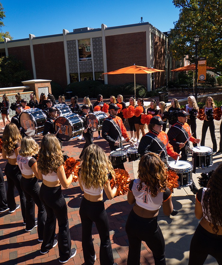 Mercer cheerleaders and Mercer dance team members cheer as Mercer band drummers play on campus during Homecoming 2018 festivities in Macon.