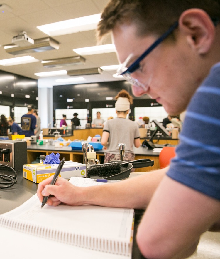 A student writes in a notebook in Mercer lab.
