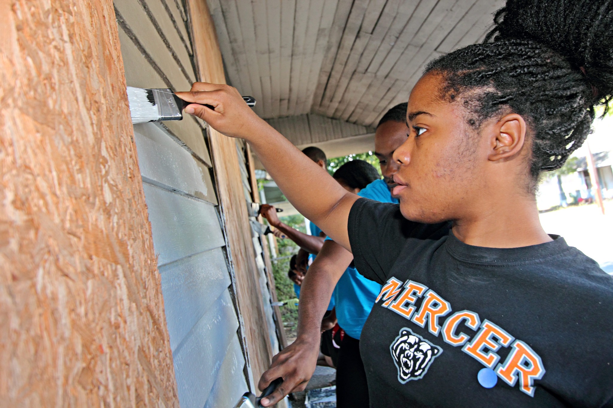 A Mercer University student paints a house.