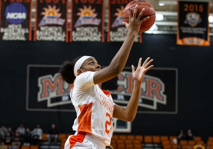 Women's basketball player shooting basketball into basket