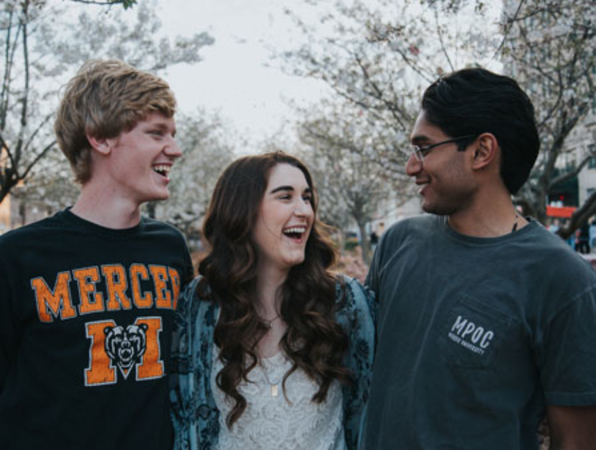 Three students hugging and smiling in downtown Macon