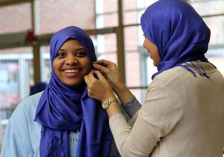 One student pins a hijab on another for World Hijab Day