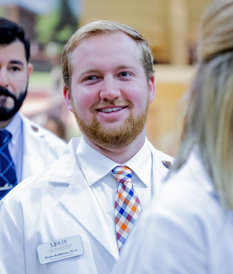 Graduate student smiles in white coat