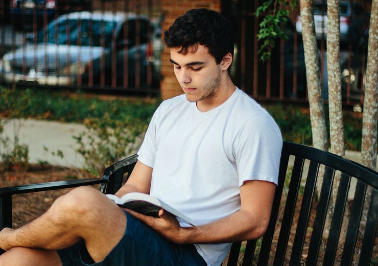 Student reading a book on campus