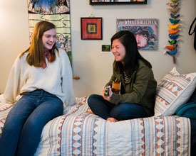 Roommates sit on bed in Legacy Hall