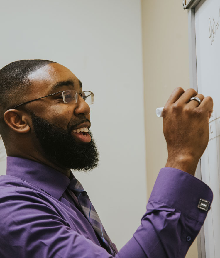 Adult student smiles while writing on board