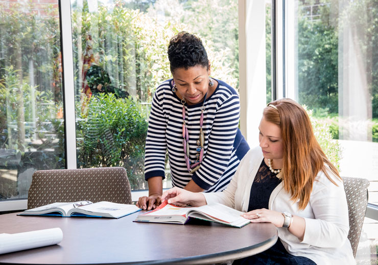 Two working adults share a textbook