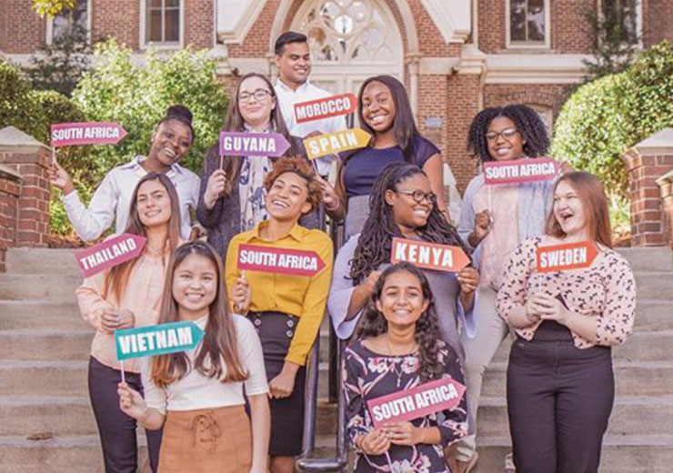 Students posing with signs of the countries they are studying abroad in this summer