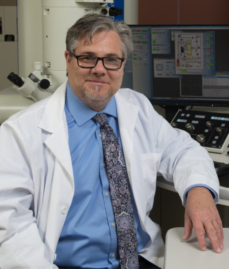 Dr. Robert Visalli sits in front of a microscope