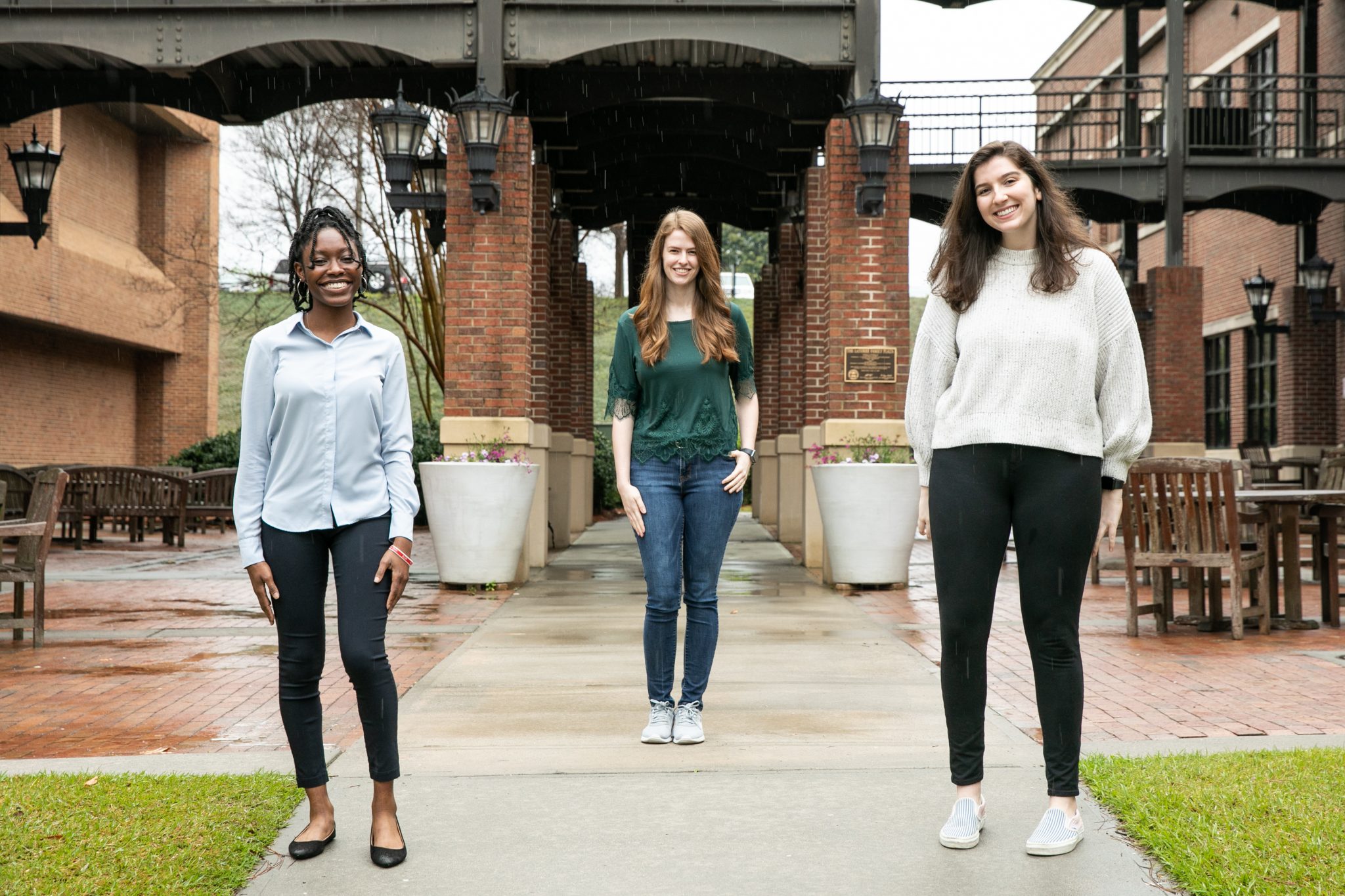 three women stand in front of a building