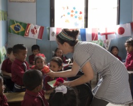a young woman talks to a child in a class full of students