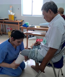 A young woman in scrubs fits a man for a prosthetic leg