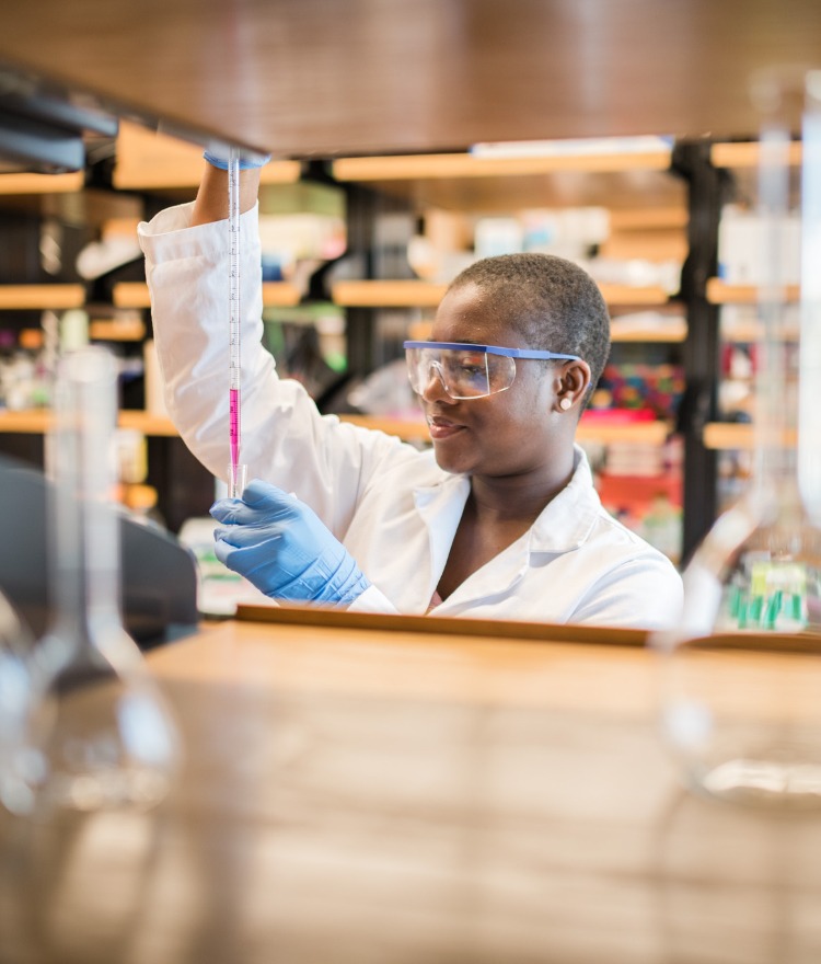A female Mercer student pipes a solution into a test tube in a lab