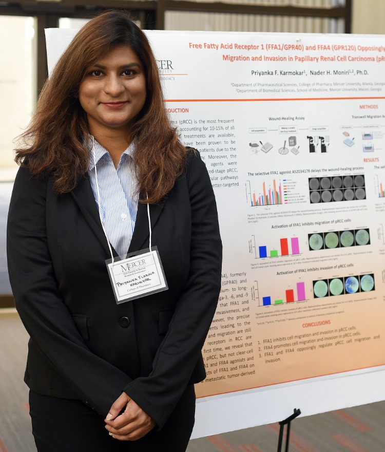 A woman stands next to a poster displaying her research