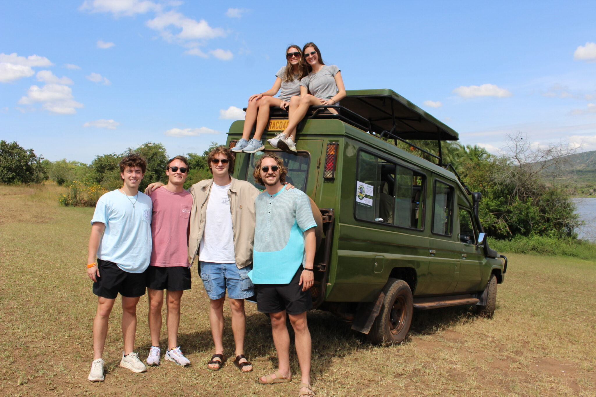 students stand in front of a green safari van