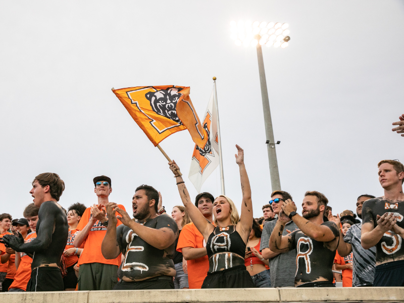 A group of students cheer in the football stands.
