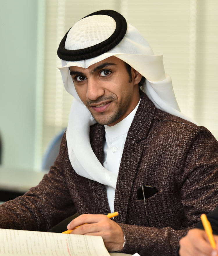 A male college student wearing a head covering looks up from writing