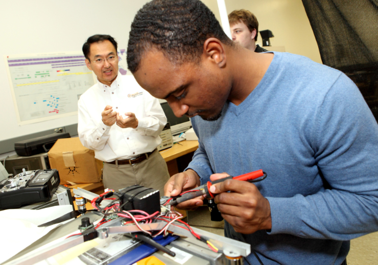 dr. choi oversees a student working on a robot in the robotics lab