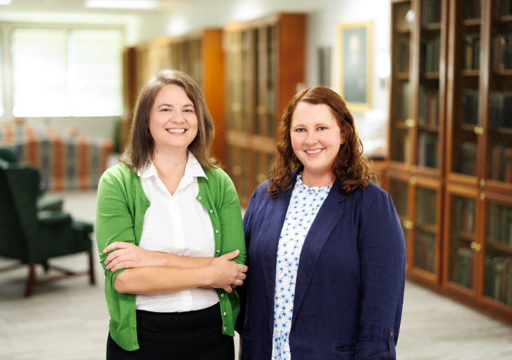 Carolann Curry and Sarah Rotschafer stand next to each other in library