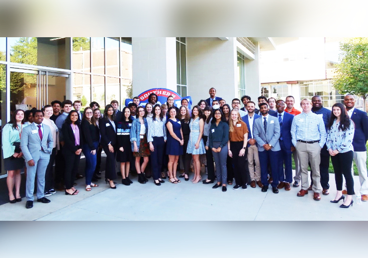 large group photo of students wearing business attire standing in front of the socon logo