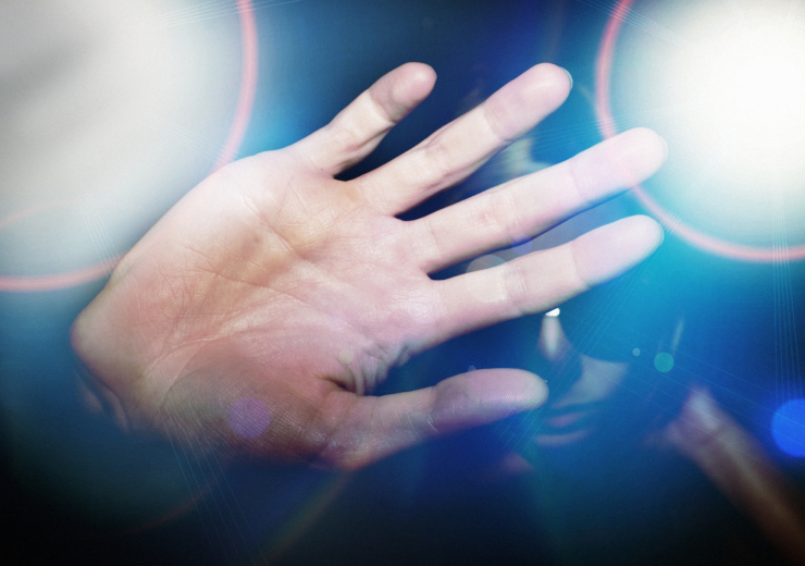man holds hand out in front of face amid flashing lights