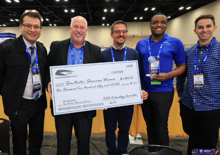 Five men stand together at an event, holding a large ceremonial check for $1,250 made out to Sim Ventor Showcase Winners.