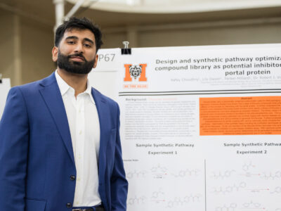 a man in a blue suit jacket stands in front of a poster