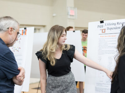 a woman points out something on her poster in front of two people
