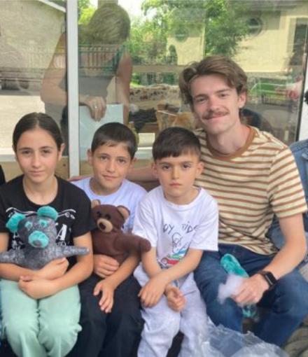 Mercer student Noah Porter sits on a bench next to three children.