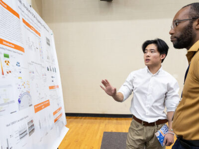 A Mercer University student presents his poster to another individual at BEAR Day.