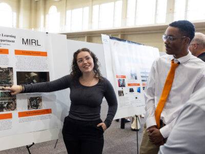 A Mercer University student presents her machine learning research poster to others at BEAR Day.