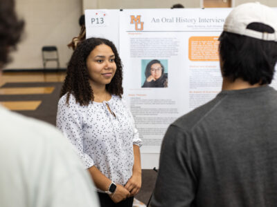 A Mercer University student stands next to her poster about an oral history interview at BEAR Day.