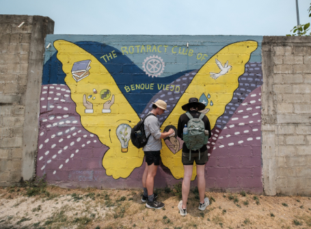 Two Mercer students stand in front of a butterfly mural in Belize.