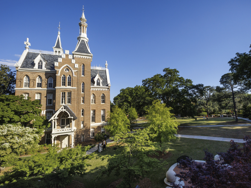 Mercer's Administration Building is surrounded by green trees and lawns under a clear blue sky.