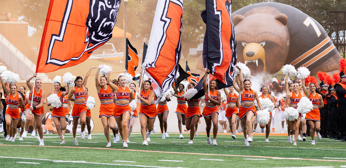 Cheerleaders and the football team running out of the tunnel