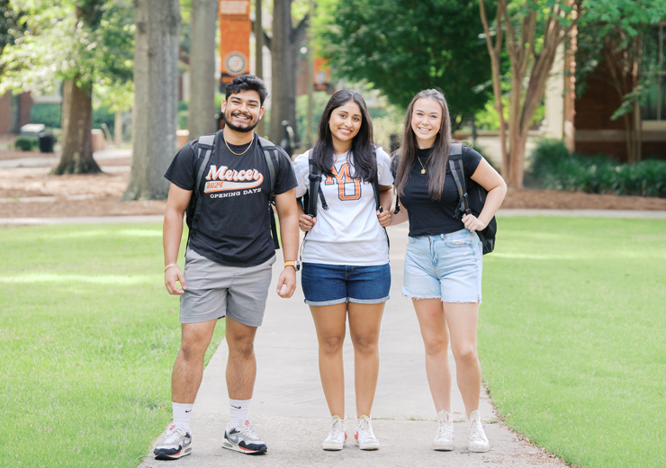 Three students posing for a photo on campus