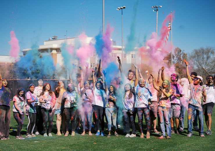 Students throwing colored chalk into the air