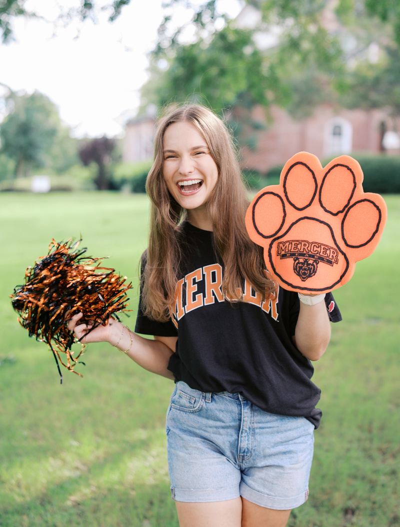 Female student holding a pom-pom and foam bear paw