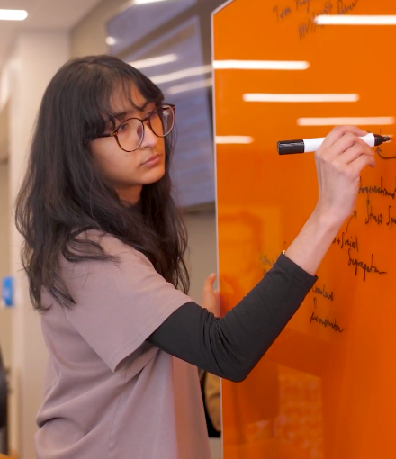 Reema Chande writes on dry erase board.