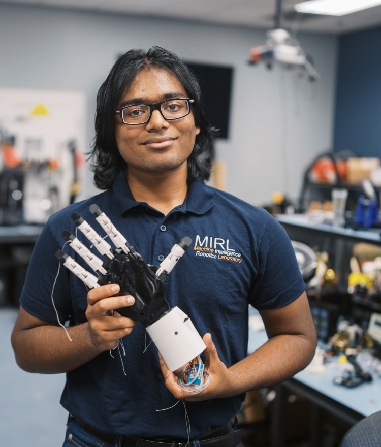 A Mercer student holds a robotic hand.