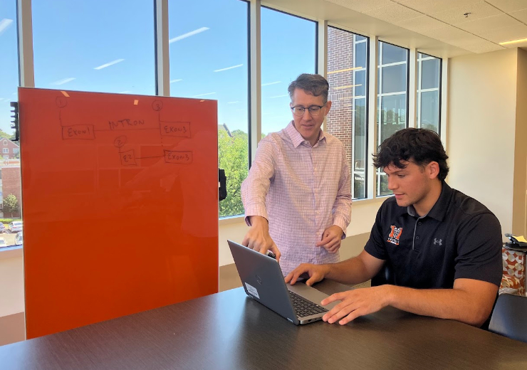 Dr. John Stanga and a Mercer student work together at a table.