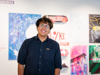 A student stands in front of art on display at the McEachern Art Center.