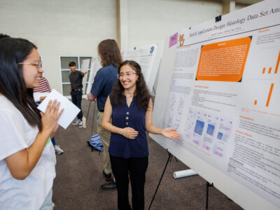 A Mercer student gestures toward her poster titled Mobile Application Design: Histology Data Set Analysis.