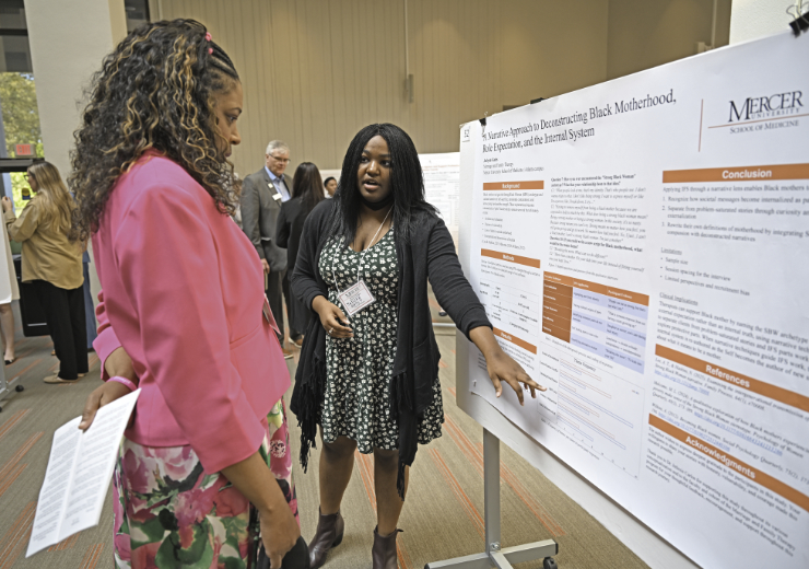 A Mercer School of Medicine student presents her research poster on Black motherhood to an attendee at the Atlanta Research Conference.