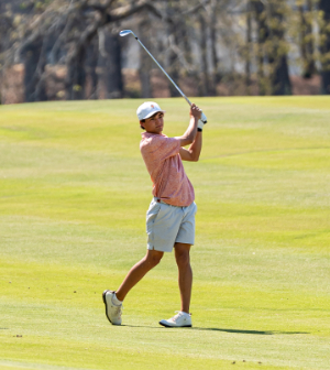 A Mercer University golfer follows through on a swing on a sunny fairway.