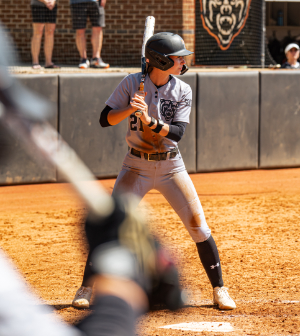 Mercer softball player #21 stands ready at the plate in batting stance during a sunny home game.