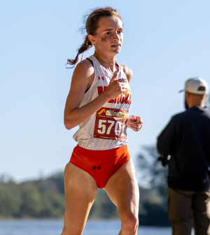 Mercer women's cross country runner #5701 competes in a race along a waterfront course on a clear sunny day.
